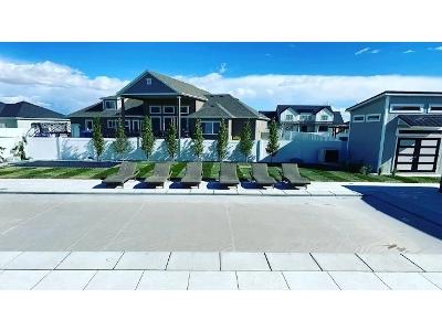 The image is an attractive, wide-angle exterior photograph of a large, modern home and community pool area, showcasing the type of meticulously planned outdoor space that Ironwood Landscaping LLC creates.